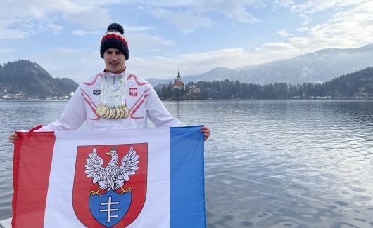 Michał Perl z flagą Legionowa na tle jeziora