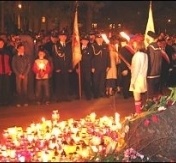 Harcerze trzymali wartę honorową z pochodniami, w dali poczty sztandarowe straży pożarnej i policji
