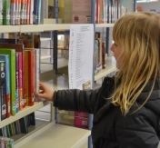 Dziewczynka sięga po książkę z półki
