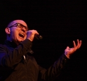 Na zdjęciu Andrzej Krzywy. Wokalista stoi na scenie.