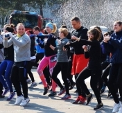 Zdjęcie: Małgorzata Piekutowicz na zdjęciu uczestnicy biegu robią rozgrzewkę na stojąco Zdjęcie: Małgorzata Piekutowicz na zdjęciu uczestnicy biegu robią rozgrzewkę na stojąco
