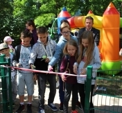 Na zdjęciu dzieci przecinają wstęgę na nowy plac zabawa. W tle Prezydent miasta Legionowo