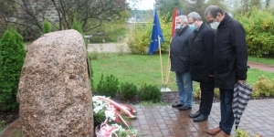 Oddanie hołdu przez trzech mężczyzn pod pomnikiem