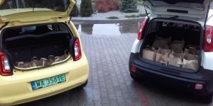 Samochody z otwartymi bagażnikami w których znajdują się paczki z jedzeniem.