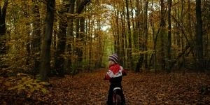 Autor: Daniel Katkowski, dziecko siedzi na rowerze w lesie.