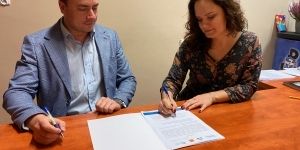 Dwie osoby przy biurku podpisujących dokument