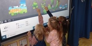 Na zdjęciu dwoje dzieci układają cyfrowe puzle na monitorze.