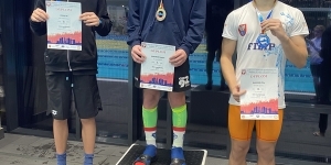 Trzech chłopców stojących na podium z medalami i dyplomami