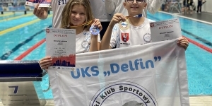 Czwórka zawodników UKS Delfin Legionowo wraz z trenerem, za nimi basen