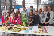 Młodzież stoi za stołem na którym przygotowano zdrowe posilki