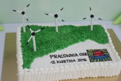 Kremowy Tort z napisem Pracownia OZE, 12 kwietnia 2016 obok logo PZSP Legionowo. Na torcie zamiast świeczek wiatraki.