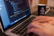 Na zdjęciu pisząca osoba na laptopie