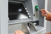 Osoba wkładająca kartę do bankomatu.