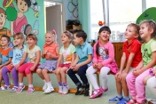 Grupa uśmiechniętych dzieci siedząca na ławkach