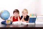 Na zdjęciu dwójka dzieci przy biurku do nauki