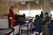 Kilka osób w pomieszczeniu, ratownik i osoba symulująca pierwszą pomoc na fantomie