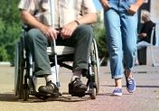 Osoba niepełnosprawna na wózku inwalidzkim oraz osoba idąca obok - pokazani od pasa w dół