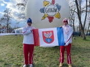 Dwóch mężczyzn trzyma flagę Legionowa, z tyłu logo Głogowa