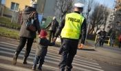 Policjant przeprowadzający dziecko przez ulicę