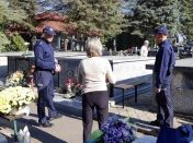 Dwaj policjanci podczas rozmowy z osobą postronną na cmentarzu