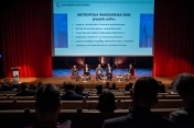 Pięć osób na scenie podczas konferencji, przed nimi widownia
