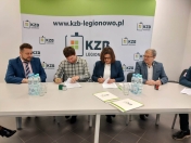 Grupa osób siedzi przy stole. Podpisanie umowy.