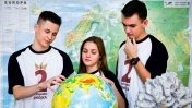Dwóch uczniów i jedna uczennica przed globusem