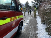 Bok auta straży pożarnej, dalej druhowie podczas interwencji