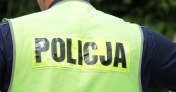 Fragment osoby z kamizelką odblaskową z napisem Policja
