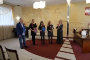 5 osób na sali z teczkami i różami w rękach