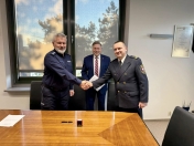 Na zdjęciu trzy osoby, dwie ściskają dłonie