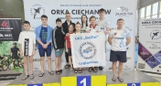 zawodnicy pozują z klubową flagą stojąc na podium