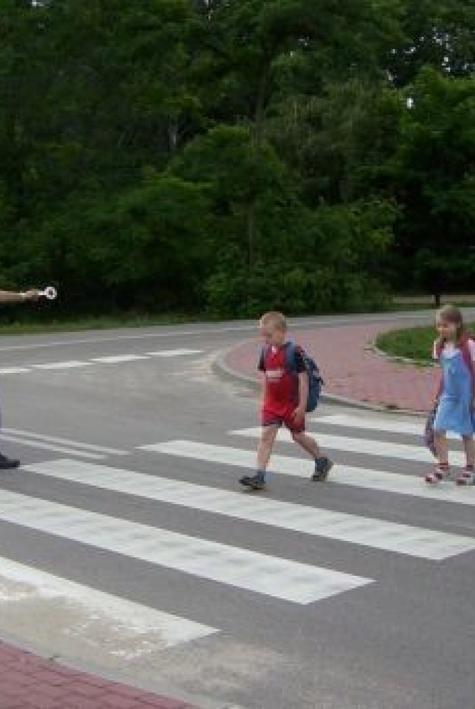 Strażnik miejski pomagający dzieciom w przejściu przez jezdnię