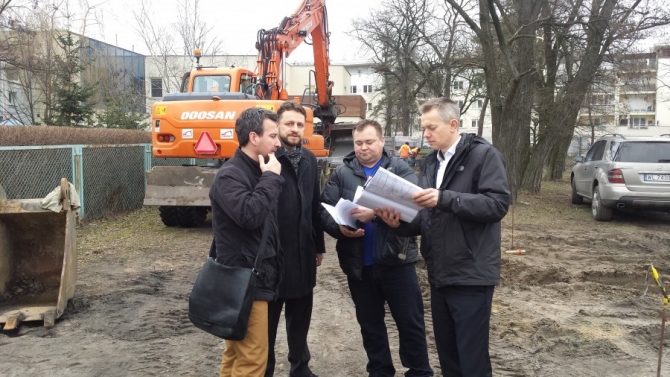 Plac budowy. Cztery osoby oglądają plany projektu.
