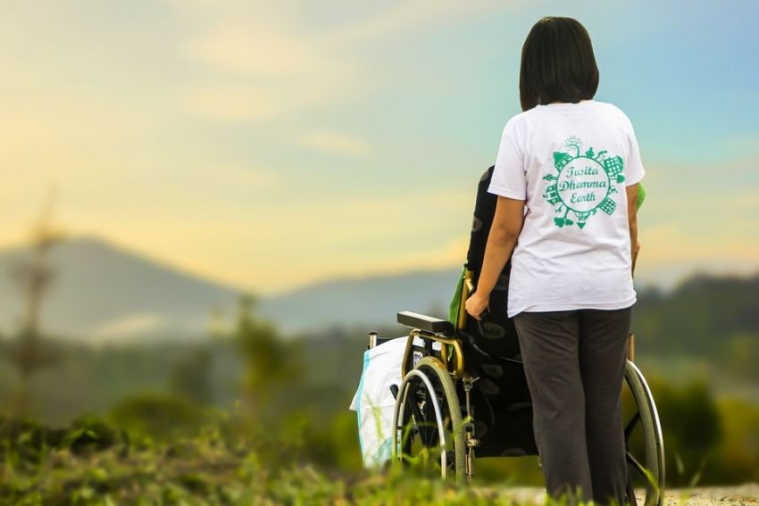 Wolontariusz pomagający osobie niepełnosprawnej na wózku
