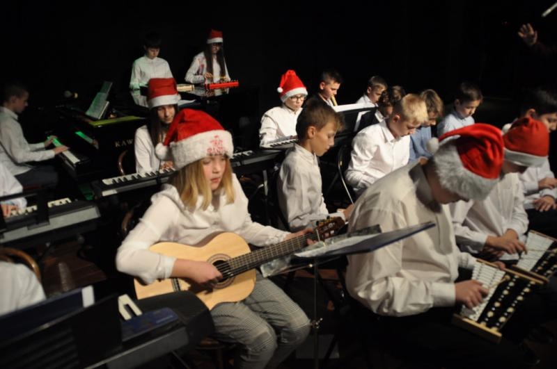 Na zdjęciu dzieci grające na gitarach oraz innych instrumentach podczas koncertu kolęd