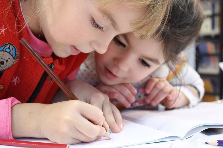 Na zdjęciu dwójka dzieci odrabiających lekcje w wieku przedszkolnym