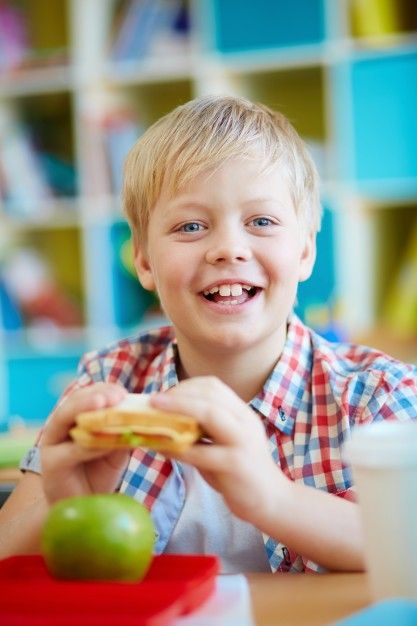 Szczęśliwe dziecko spożywające kanapkę/fot. freepik