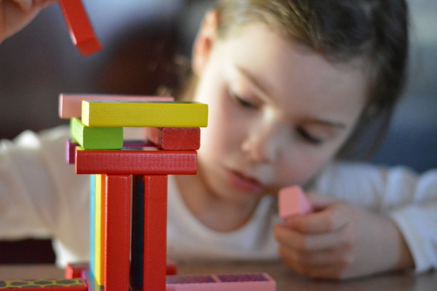 Na zdjęciu dziecko układające wieżę z klocków