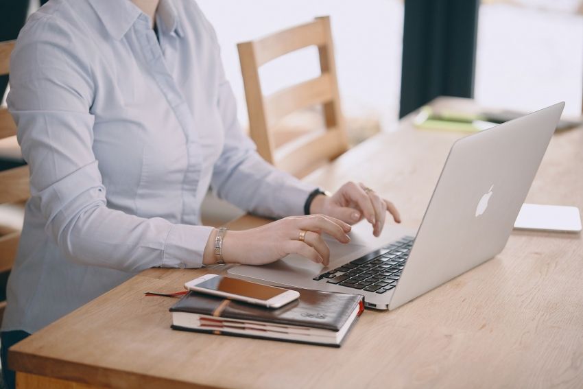 Na zdjęciu: kobieta przy stole podczas pracy na laptopie