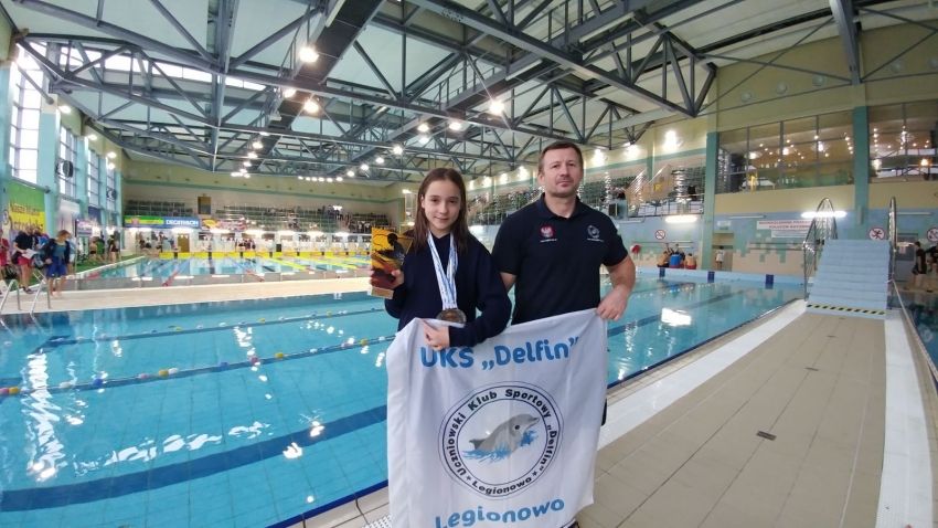 Trener i zawodniczka klubu UKS Delfin, w tle basen.