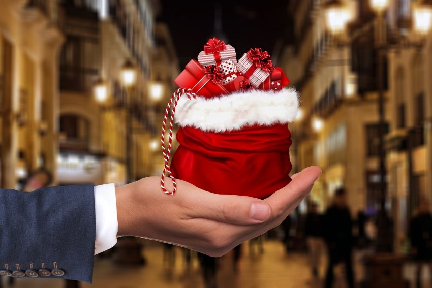 Na zdjęciu prezenty świąteczne w worku umieszczonym na otwartej dłoni.