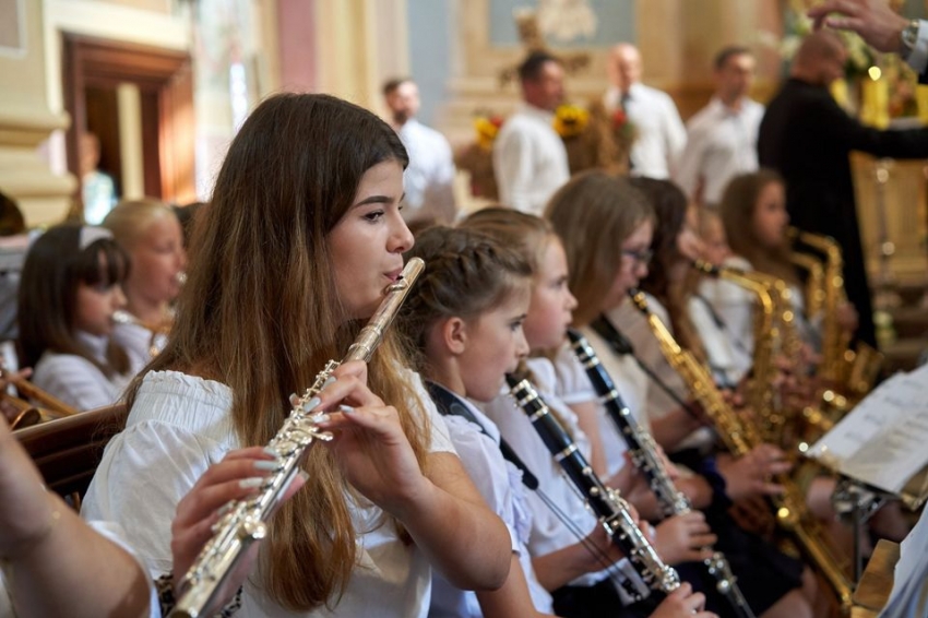 Grupa dziewcząt gra na różnych instrumentach dętych.