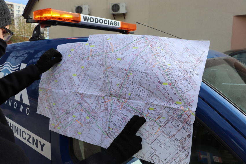 Osoba trzymająca mapę rozłożoną na samochodzie wodociągów