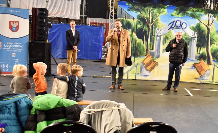 Na zdjęciu widać trzech mężczyzn na scenie, przed nimi stojące dzieci