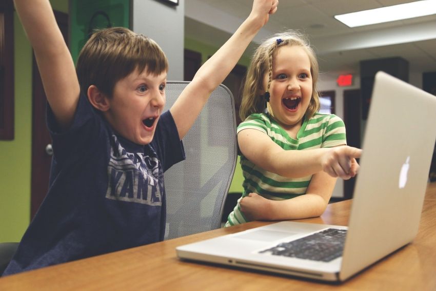 Chłopiec i dziwczynka cieszące się przed laptopem