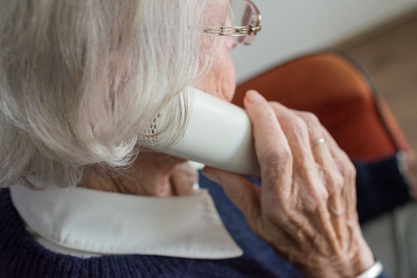 Starsza kobieta trzymająca słuchawkę telefonu przy uchu