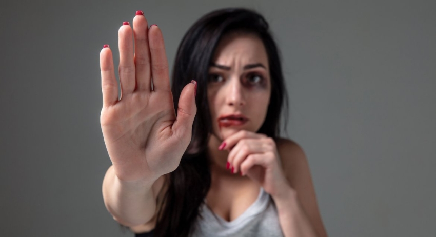Kobieta z zakrwawionymi ustami i wyciągniętą dłoń na znak stop