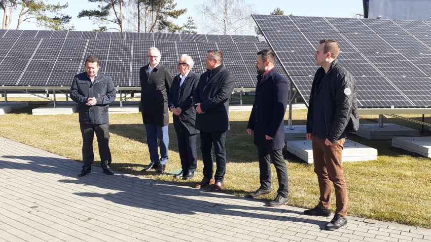 Sześciu mężczyzn na tle paneli fotowoltaicznych
