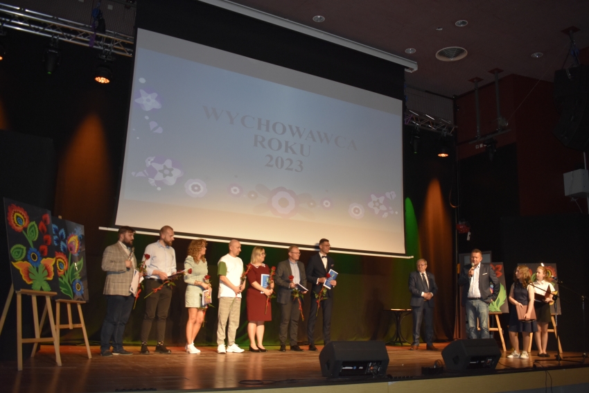 Osoby z dyplomami i kwiatami na scenie sali widowiskowej